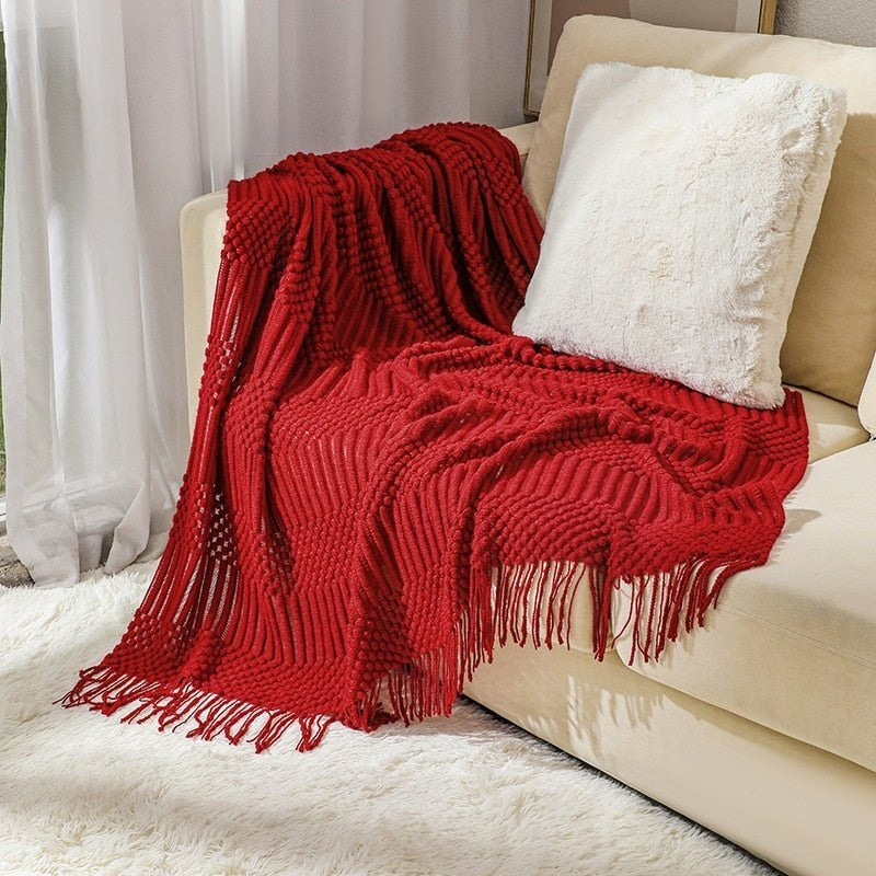 Knitted throw with a Scandinavian pattern and tassels over a chair - red