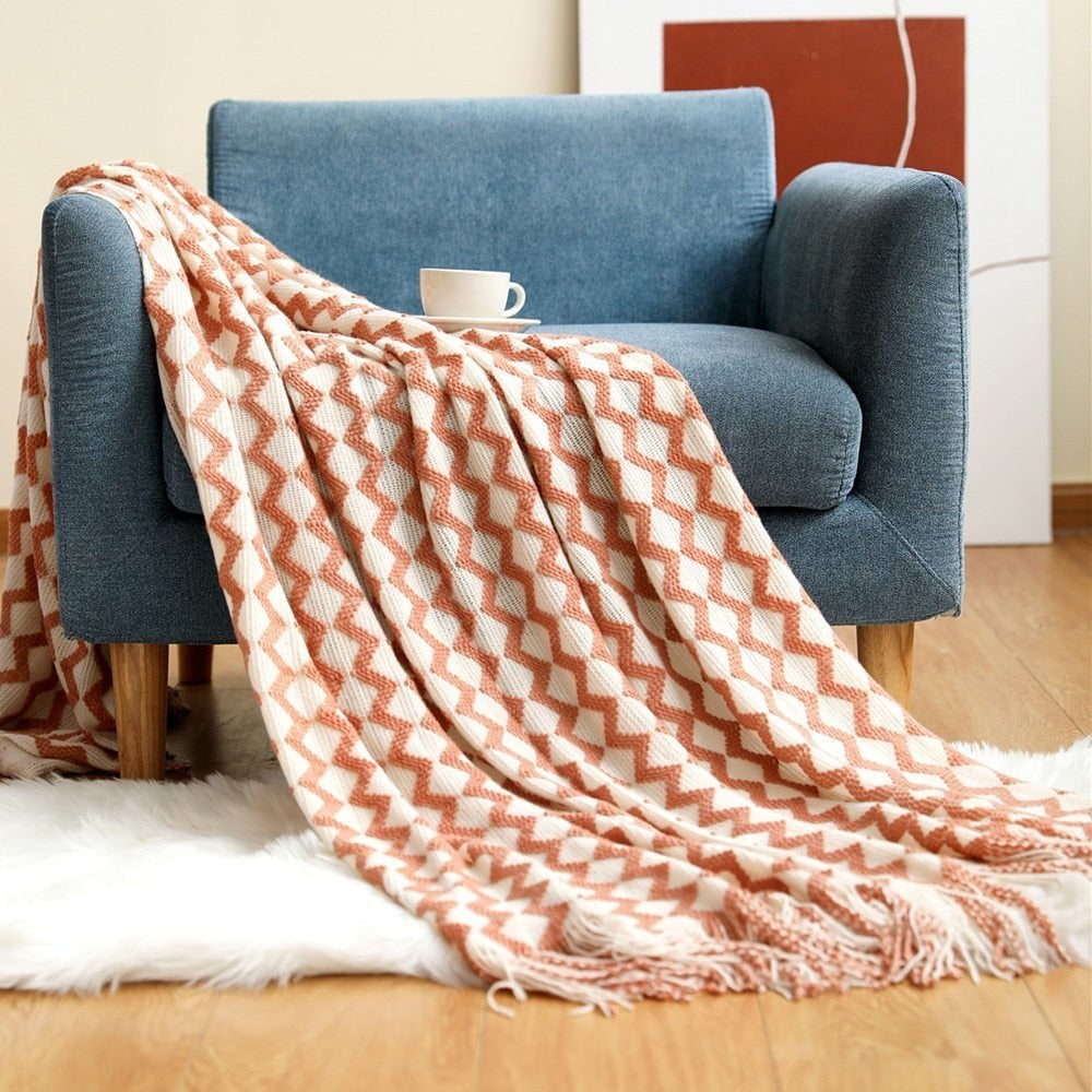 Knitted throw with a Scandinavian pattern and tassels over a chair - salmon and white zigzag