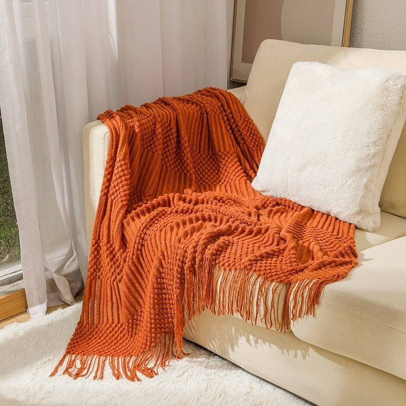 Knitted throw with a Scandinavian pattern and tassels over a chair - orange