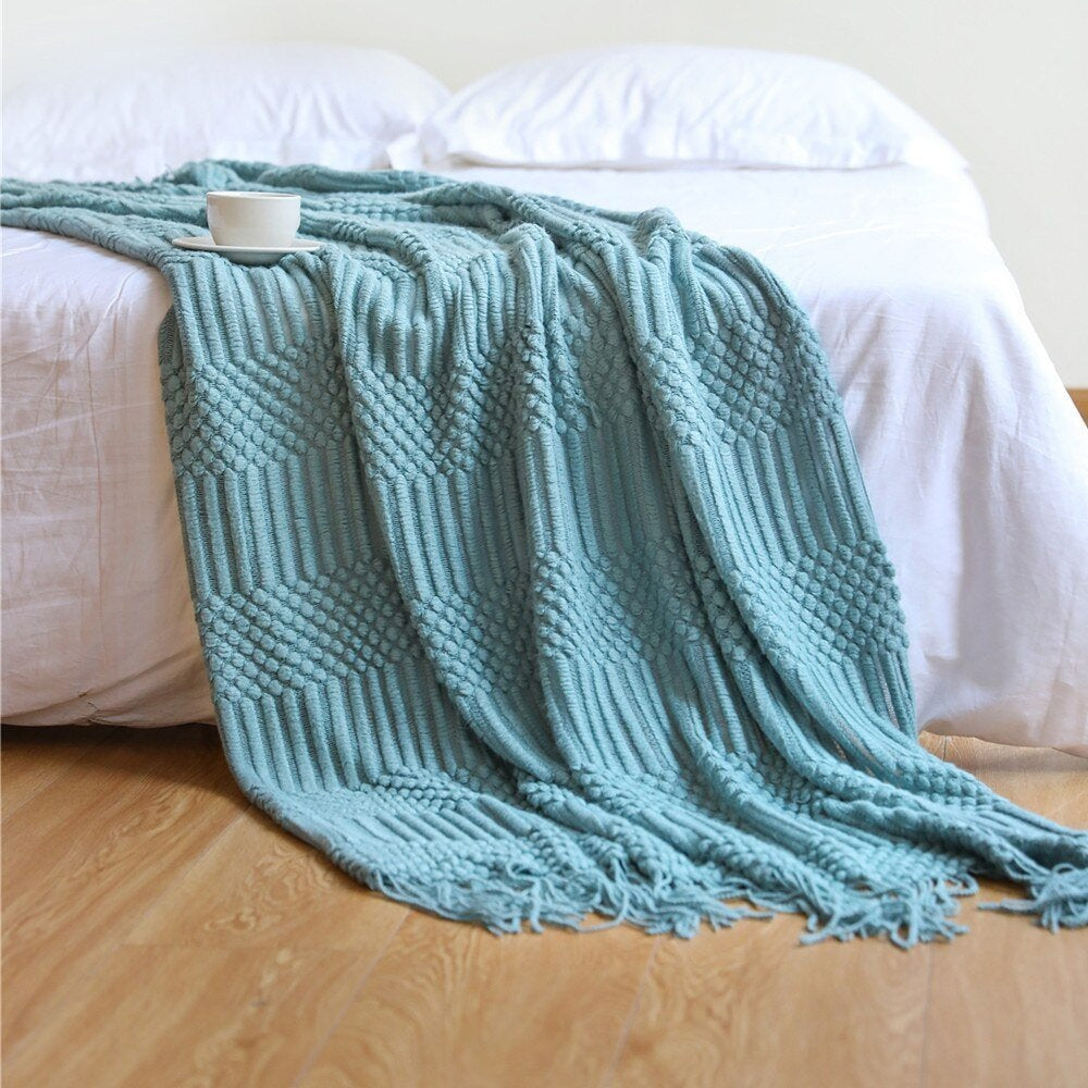 Knitted throw with a Scandinavian pattern and tassels over a chair - aqua