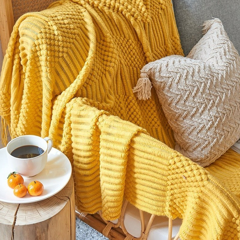 Knitted throw with a Scandinavian pattern and tassels over a chair - yellow
