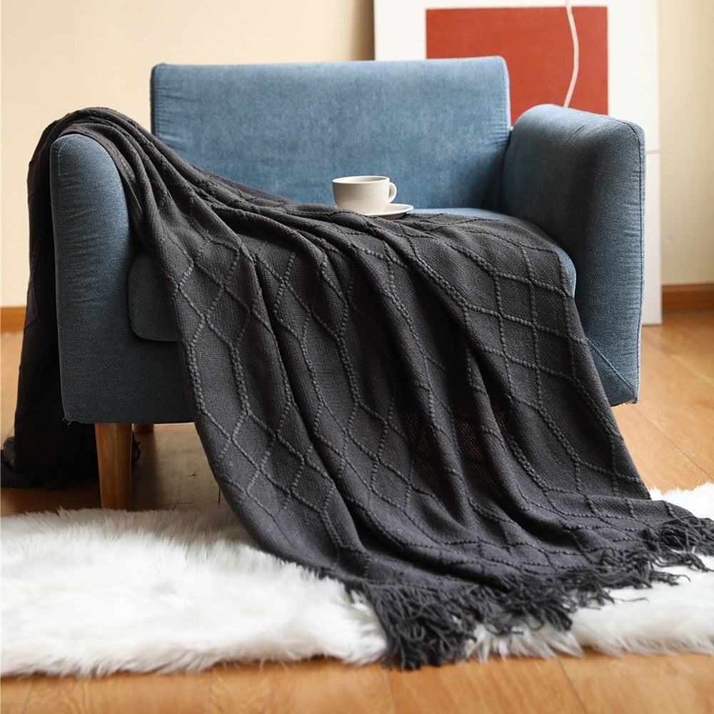 Knitted throw with a Scandinavian pattern and tassels over a chair - black