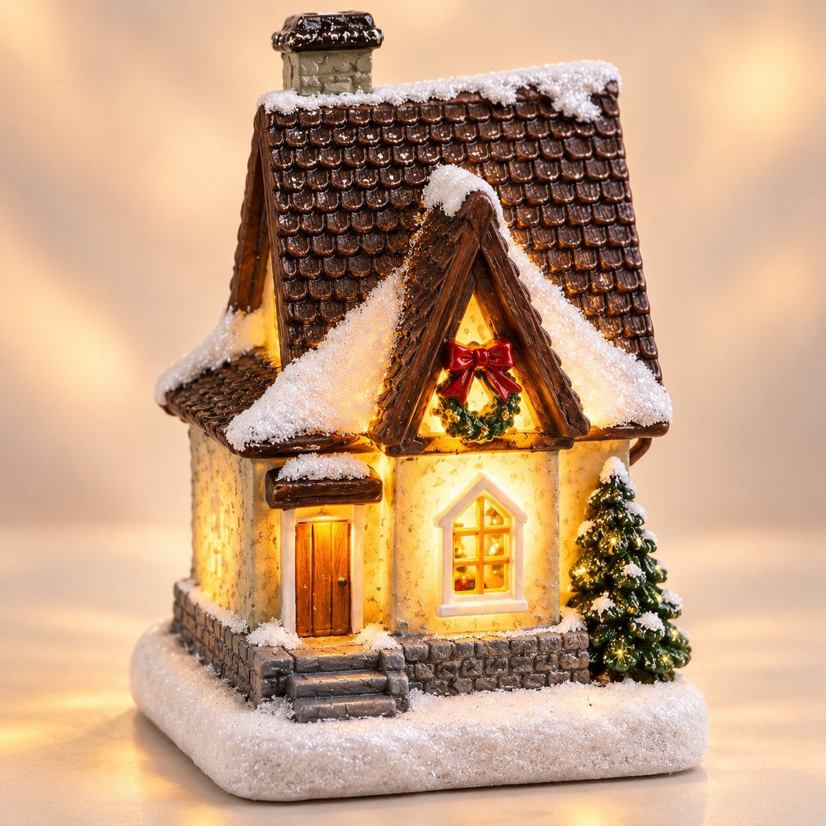 Light-up Christmas house with snow on the roof - cottage with brown roof
