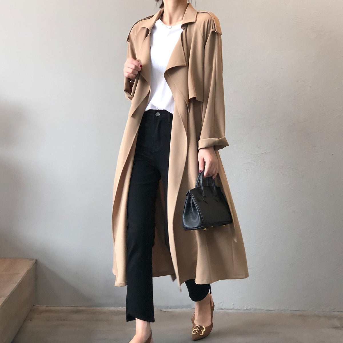 Women's longline trench coat with wide draped lapels and a tie belt