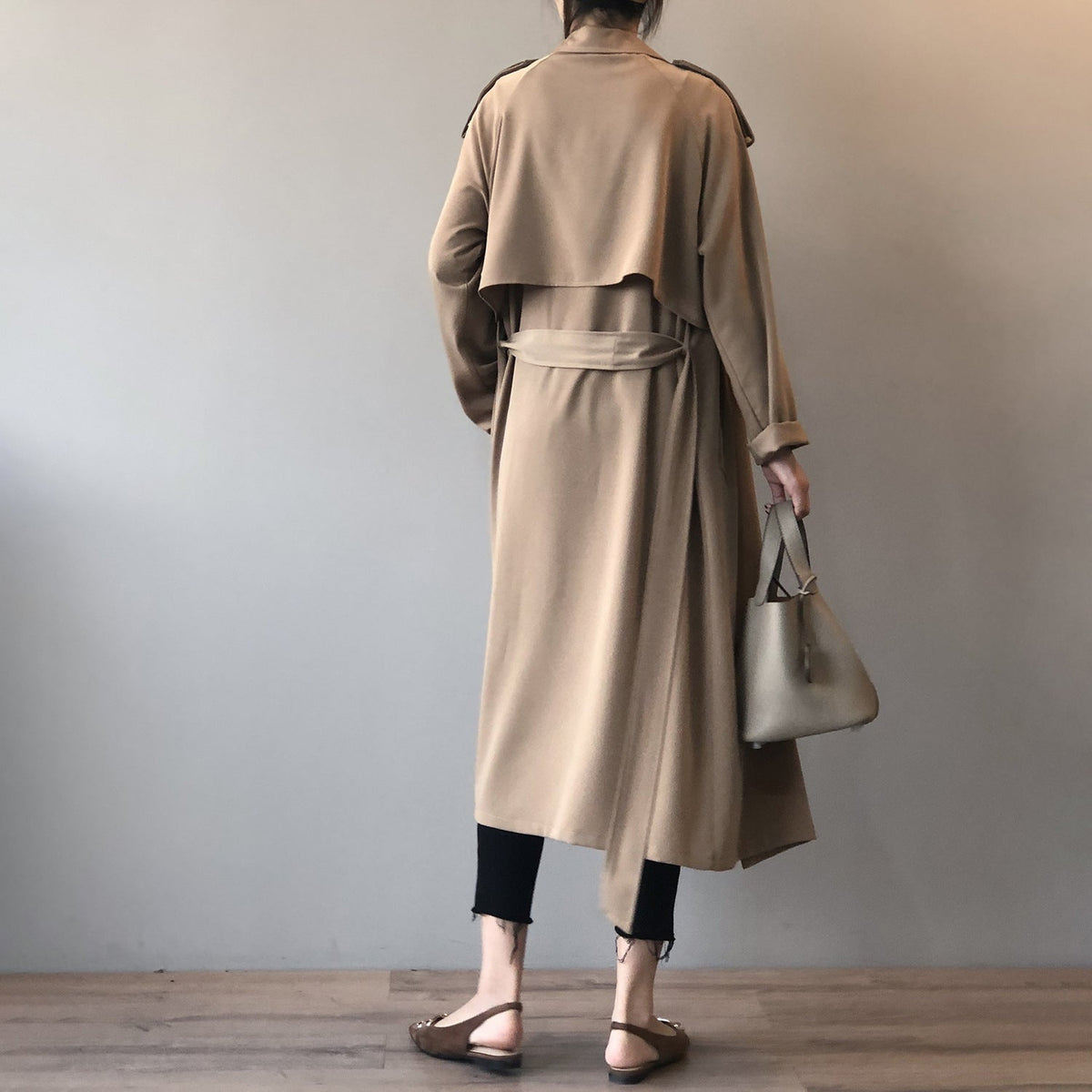 Women's longline trench coat with wide draped lapels and a tie belt