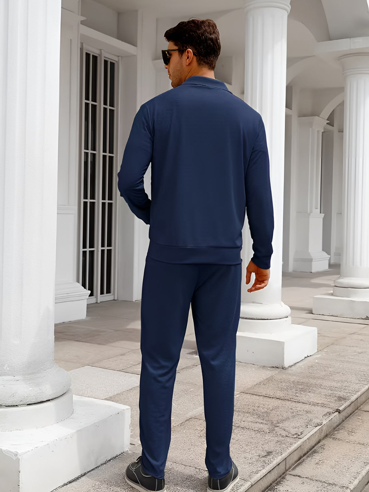 Man wearing the navy two-piece tracksuit, back view