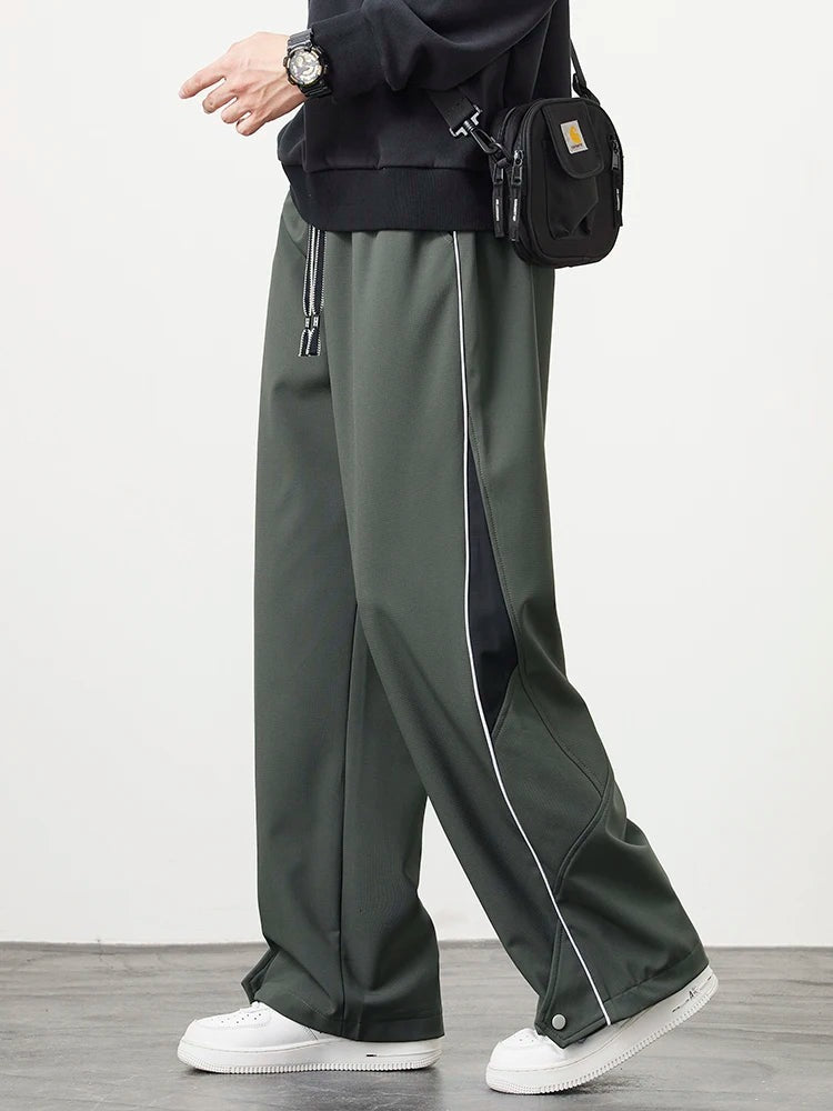 Men's wide-leg track trousers with white piping, a contrast panel on the lower leg and popper hems - army green