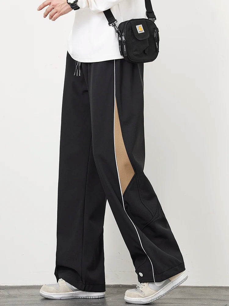 Men's wide-leg track trousers with white piping, a contrast panel on the lower leg and popper hems - black