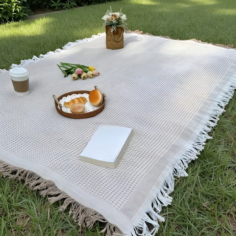 Picnic blanket of 180 x 180 cm with a waffle weave and fringe on the grass - white and beige