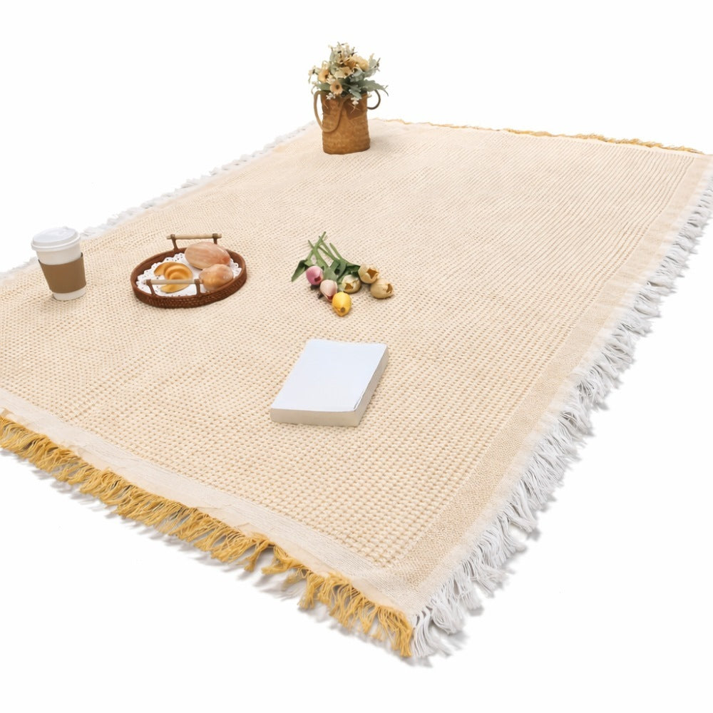Picnic blanket of 180 x 180 cm with a waffle weave and fringe on the grass - yellow and white