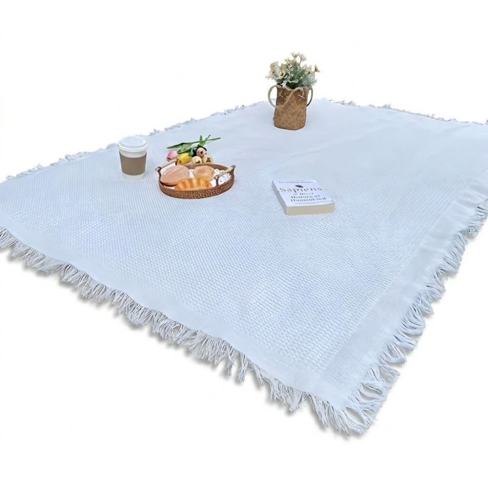 Picnic blanket of 180 x 180 cm with a waffle weave and fringe on the grass - white