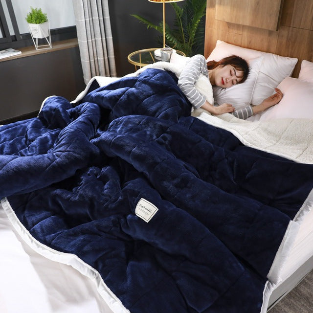 Quilted flannel fleece blanket with a sherpa reverse on a bed - navy