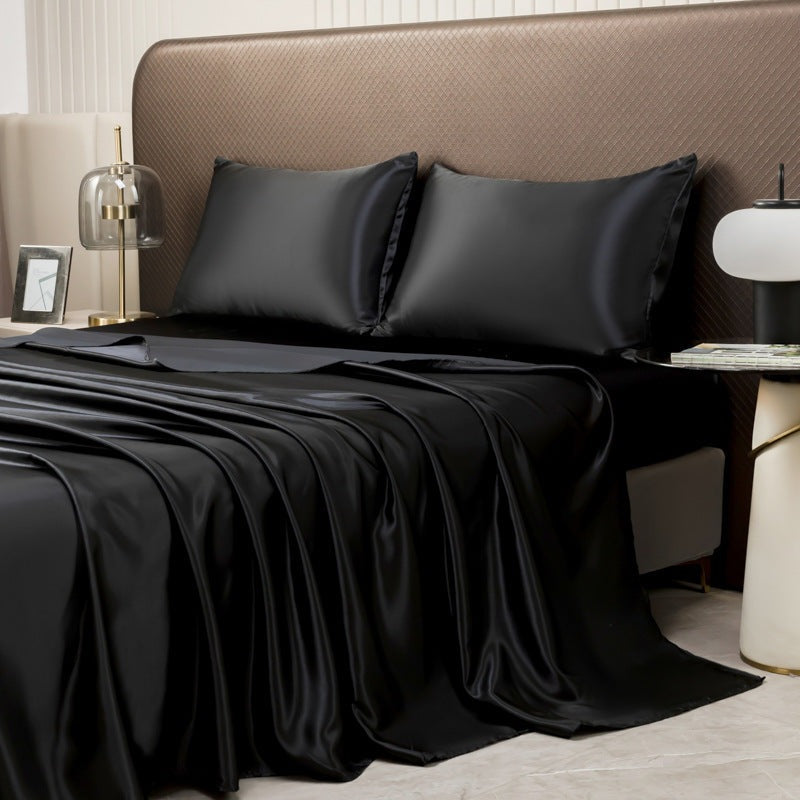 Satin sheet set with fitted sheet, flat sheet and two pillowcases on a bed - black