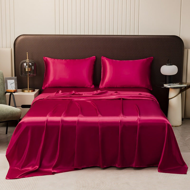 Satin sheet set with fitted sheet, flat sheet and two pillowcases on a bed - wine red