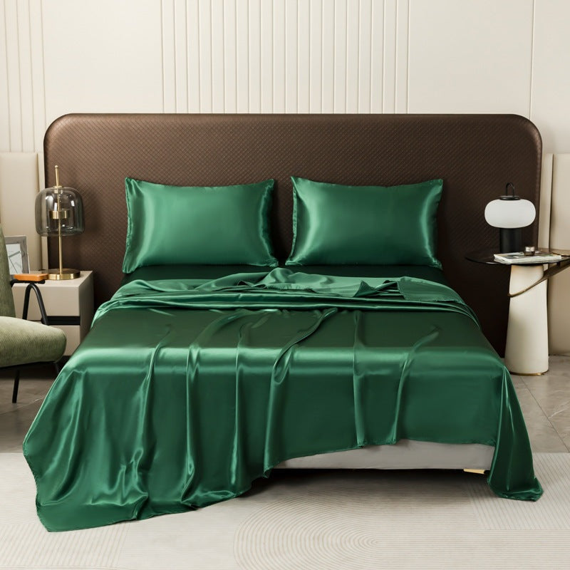 Satin sheet set with fitted sheet, flat sheet and two pillowcases on a bed - emerald green