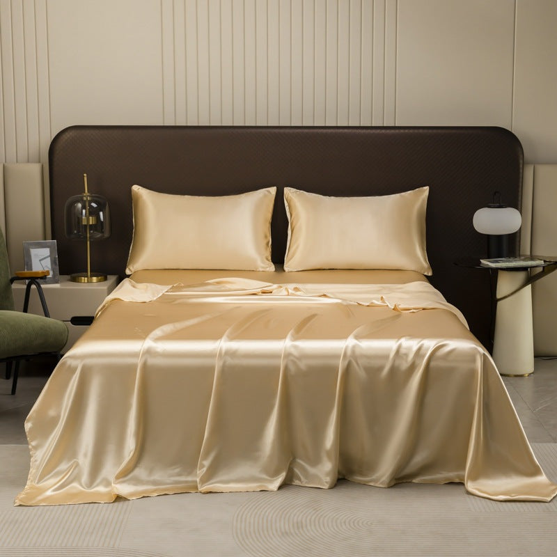 Satin sheet set with fitted sheet, flat sheet and two pillowcases on a bed - champagne