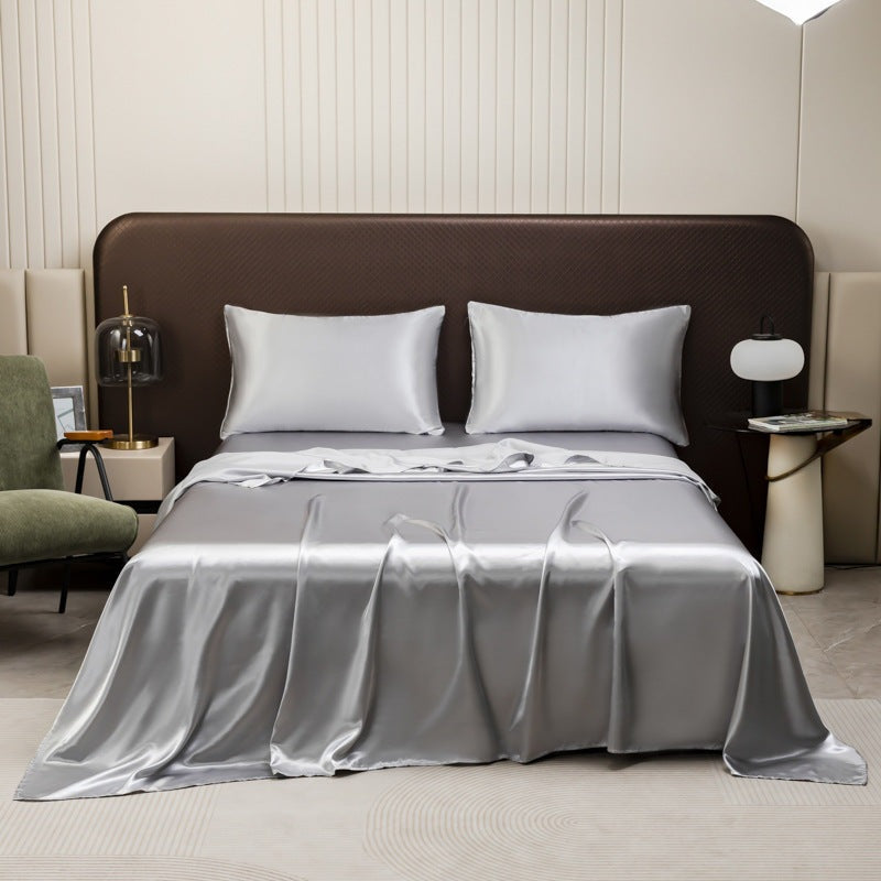 Satin sheet set with fitted sheet, flat sheet and two pillowcases on a bed - silver grey