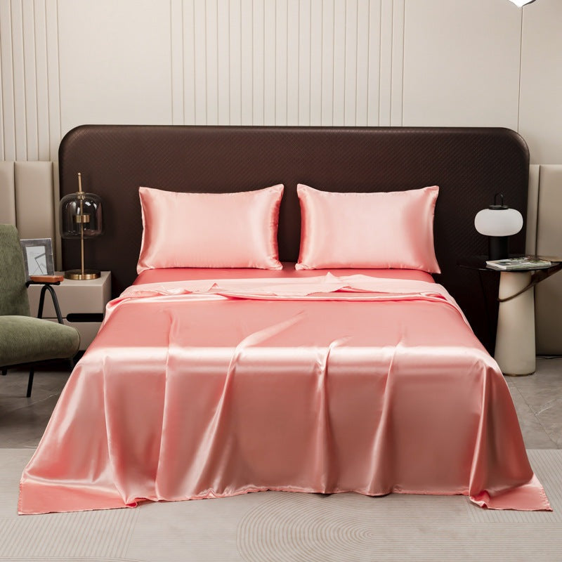 Satin sheet set with fitted sheet, flat sheet and two pillowcases on a bed - salmon pink