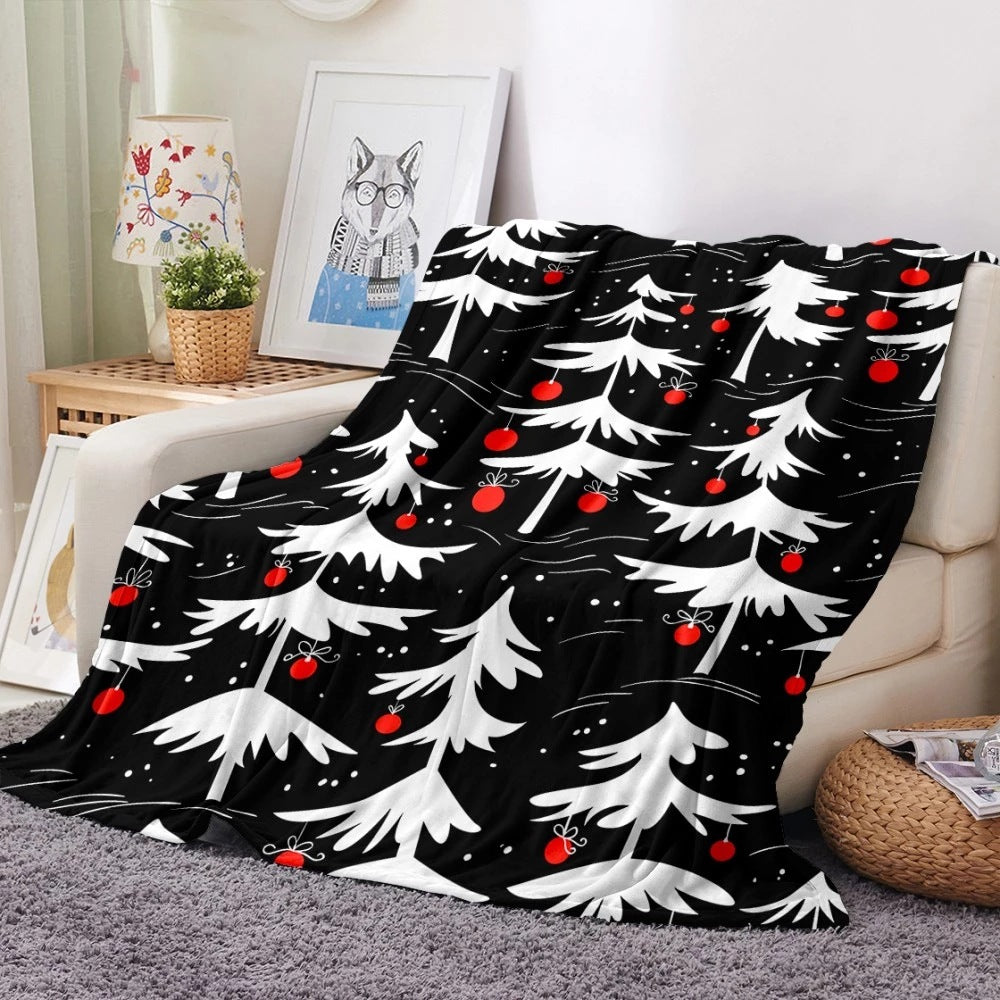 Soft fleece Christmas blanket with an all-over festive print on a sofa - black with white trees