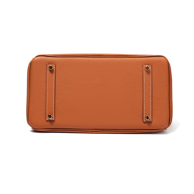 Structured top handle bag with two rolled handles, a flap with turn lock and a padlock