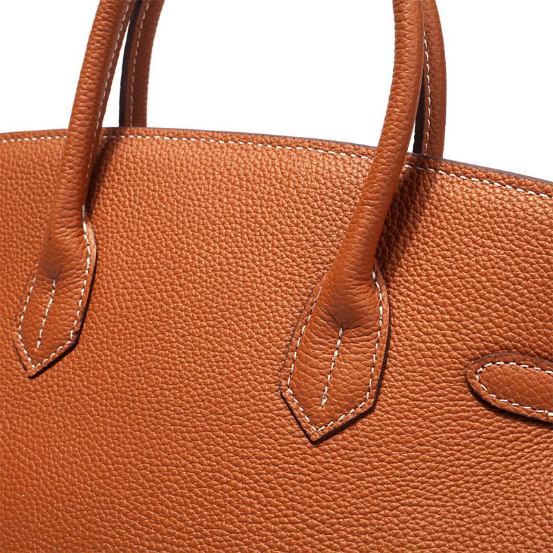 Structured top handle bag with two rolled handles, a flap with turn lock and a padlock