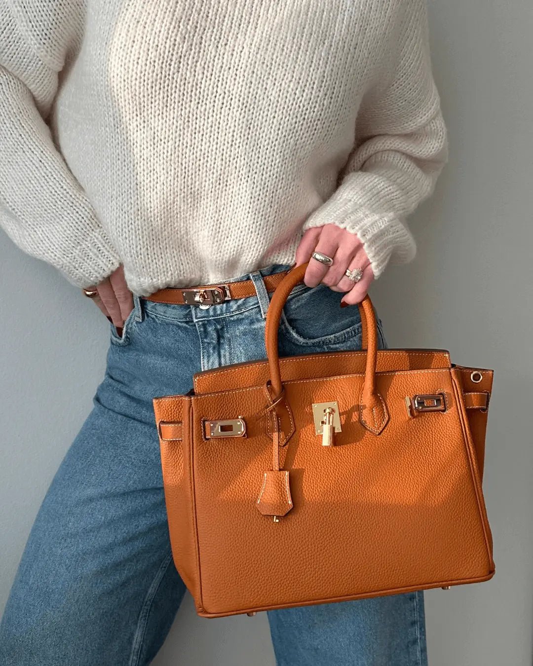 Structured top handle bag with two rolled handles, a flap with turn lock and a padlock