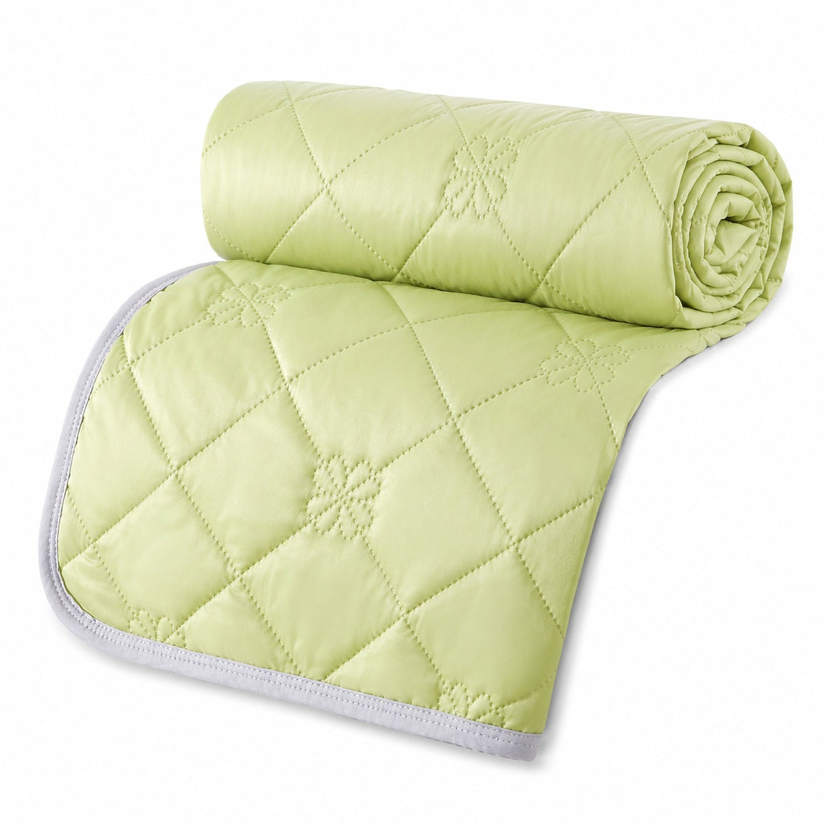 Reversible summer blanket with diamond and floral stitching on a bed - lime green