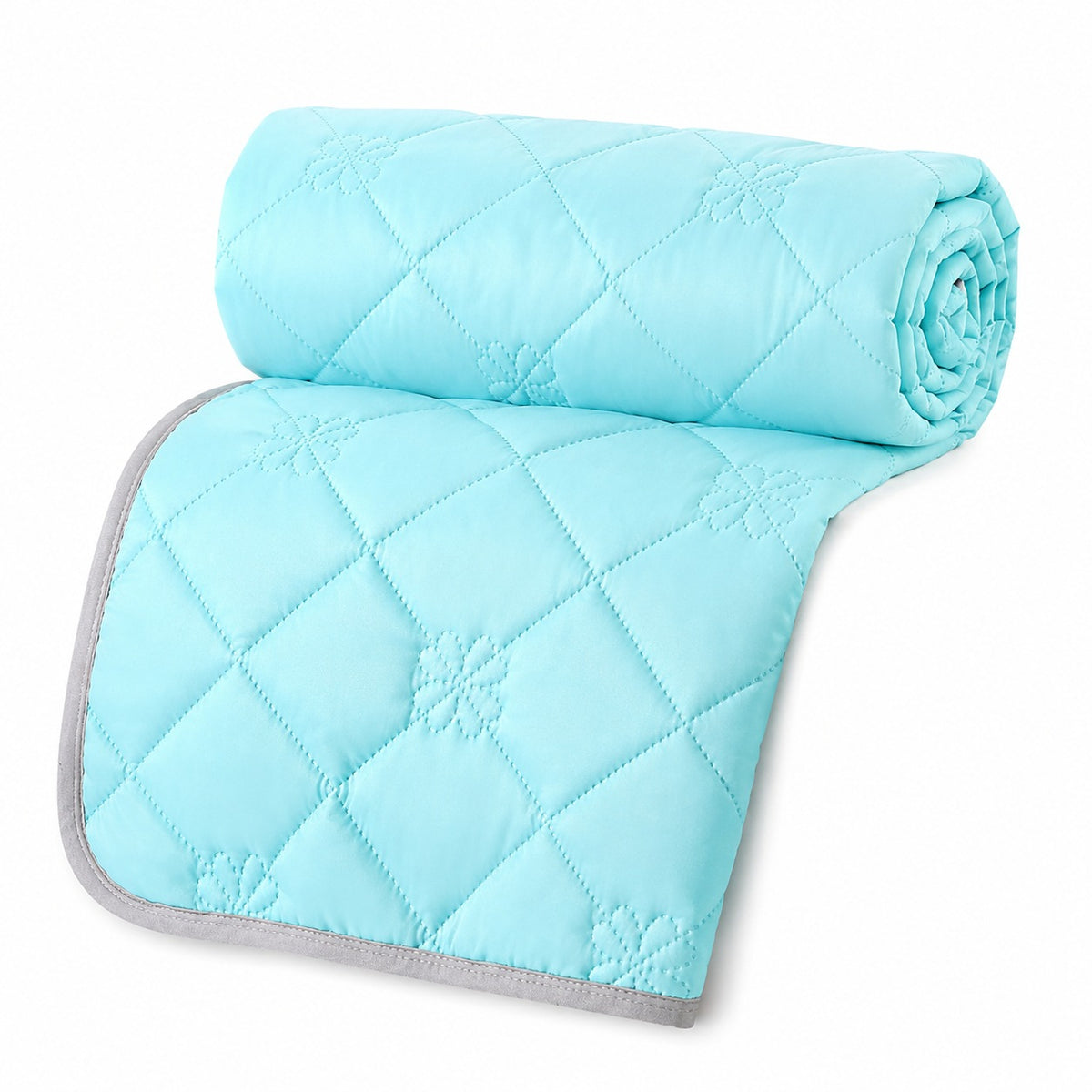Reversible summer blanket with diamond and floral stitching on a bed - aqua blue