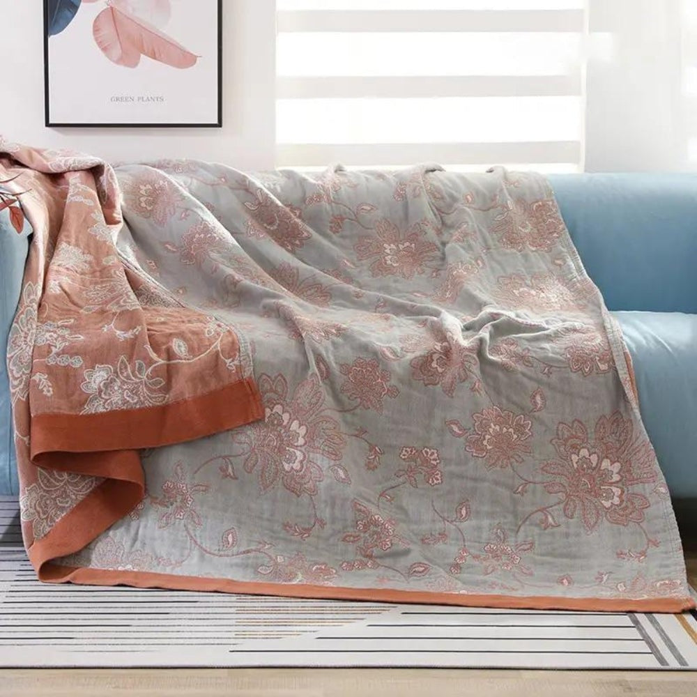 Summer blanket with a jacquard floral pattern over a sofa - light blue/rust