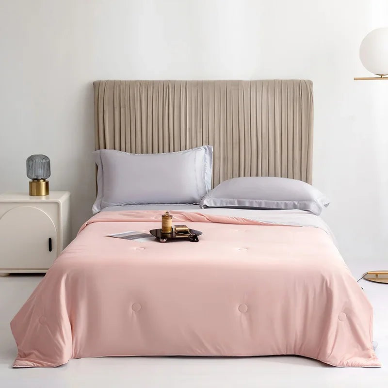 Reversible summer blanket with a grey underside on a double bed - peach pink
