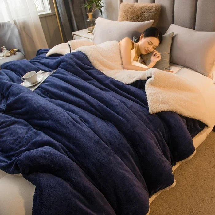 Thick sherpa blanket with a velvet-soft side on a bed - navy