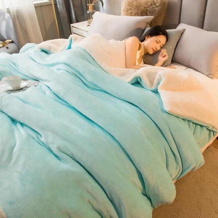 Thick sherpa blanket with a velvet-soft side on a bed - aqua blue