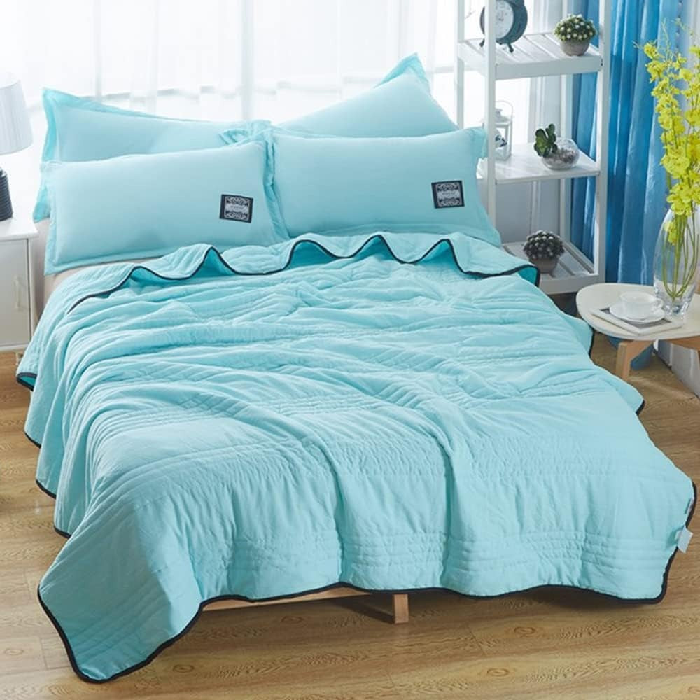 Thin quilted summer blanket with piping on a made bed - aqua blue