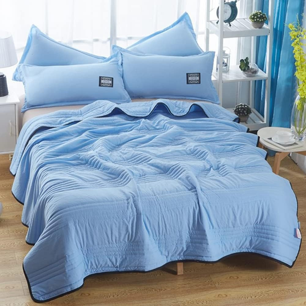 Thin quilted summer blanket with piping on a made bed - sky blue