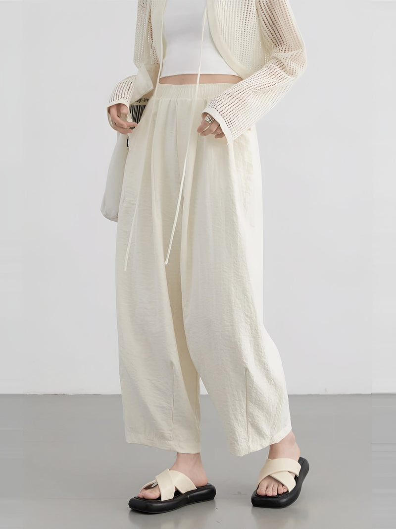 Women's cream wide-leg trousers with pleats, worn with an open cardigan