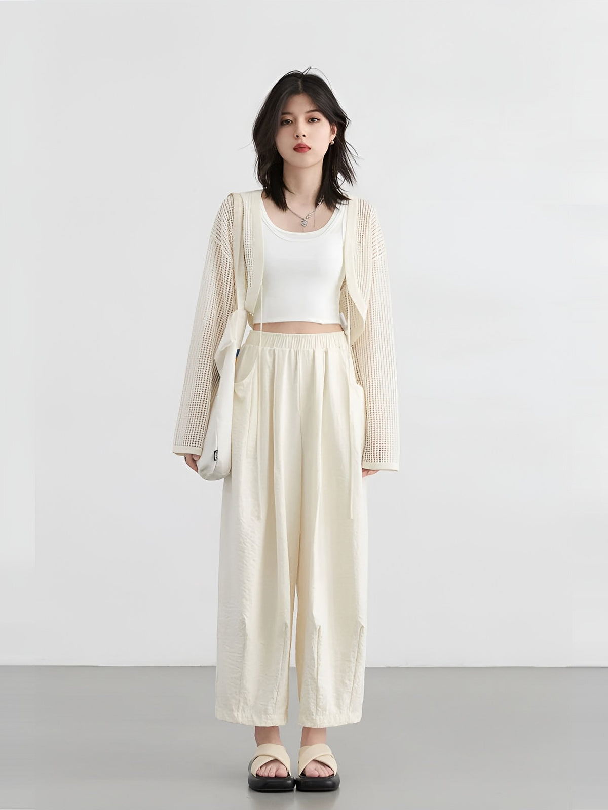 Model wearing cream wide-leg trousers with a white top and cardigan